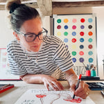 Alma Singer drawing a red toadstool for Earthling's nursery art collection