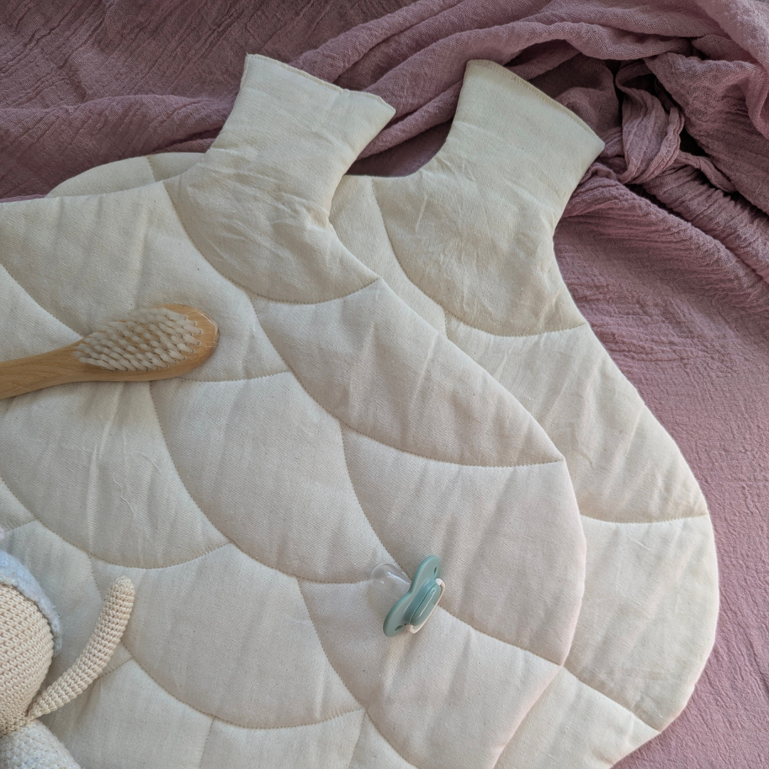 Natural quilted baby changing mat with a wooden brush on a pink blanket