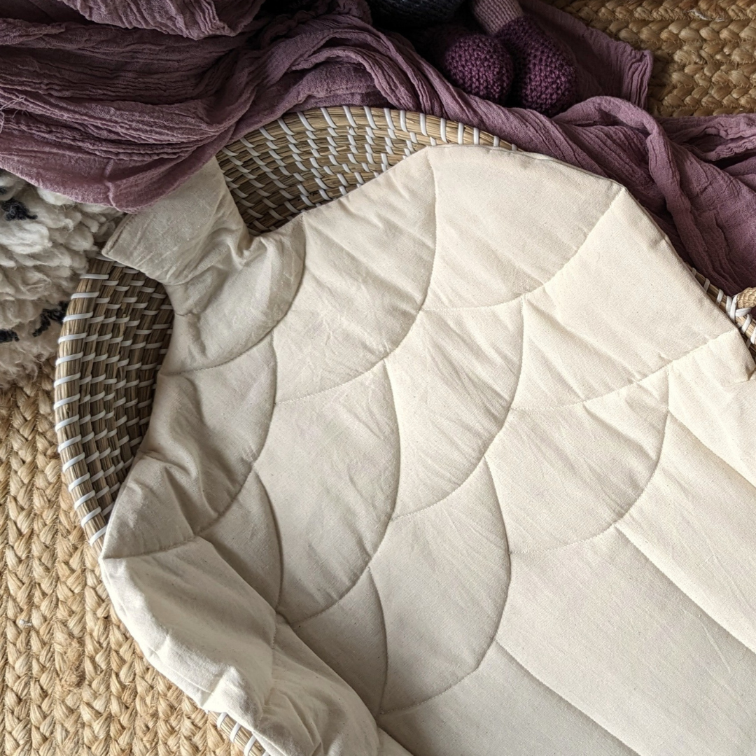 Close up of an acorn baby changing mat made out of cotton with a natural seagrass baby changing basket in the background