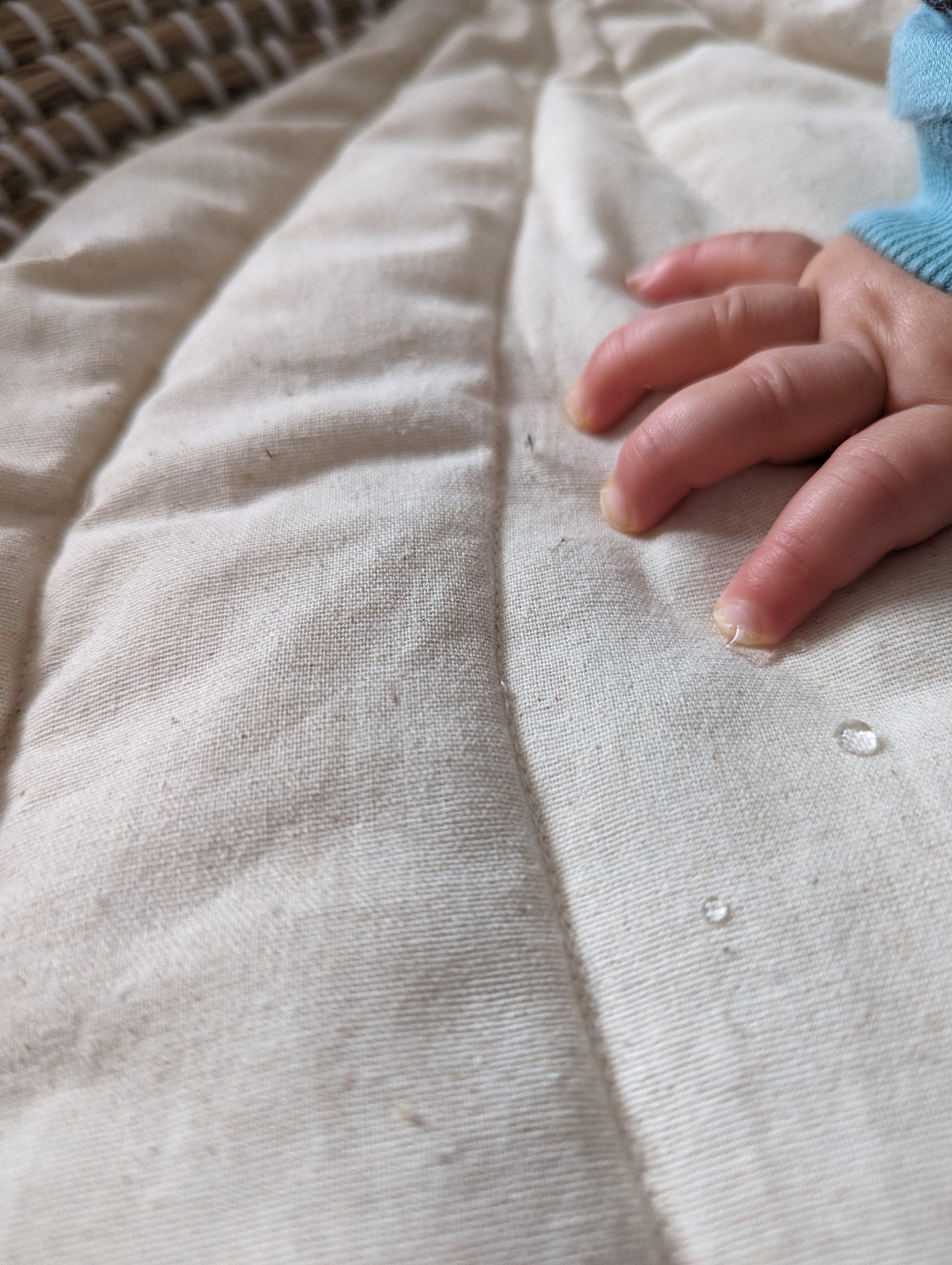 baby's hand stroking white soft cotton baby changing mat