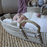 Newborn baby lying in a natural woven Moses basket on a jute rug, wrapped in a soft star-print swaddle – ideal for eco-conscious new mums.